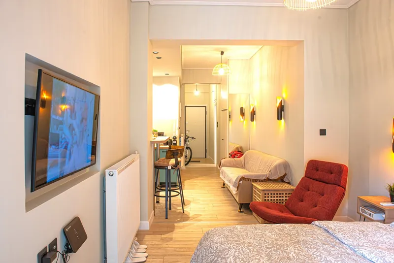 The bed facing the wall TV, with the kitchen beyond