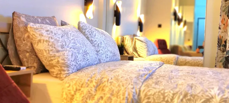 The made bed under warm wall lights