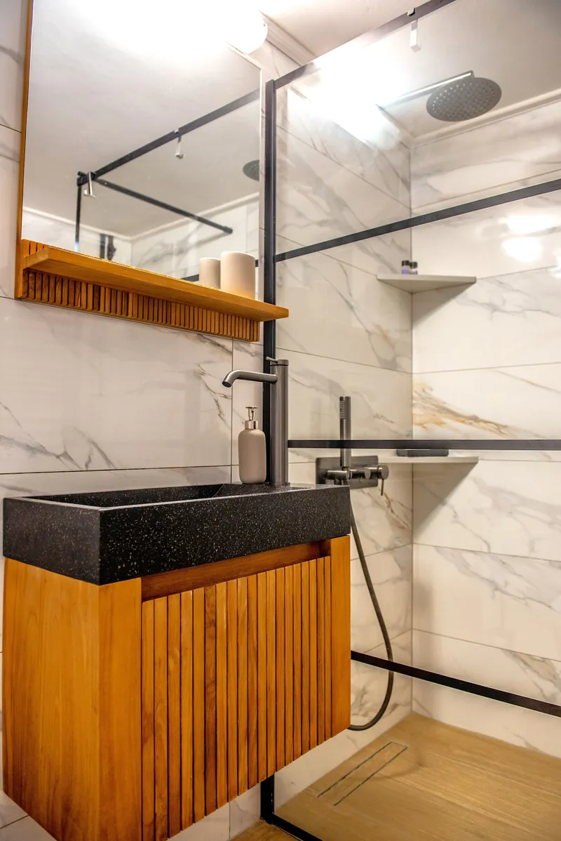 The walk-in shower with marble tiles and an oak vanity